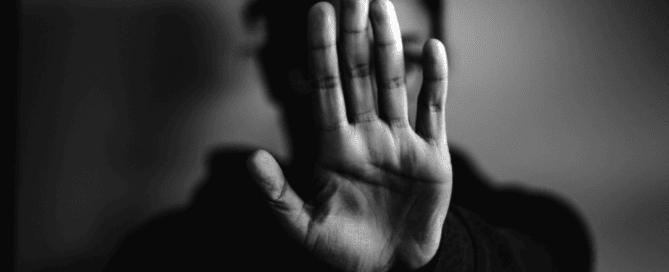 Sicht auf eine Person, die die Hand in Abwehrposition zeigt, schwarz-weiß, moderne Fotografie, Ausdruck von Zurückweisung.