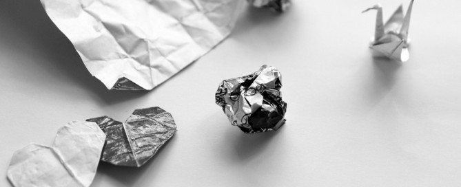 Alttext: Zerknautschtes Papier und Origami-Tier auf weißem Hintergrund.